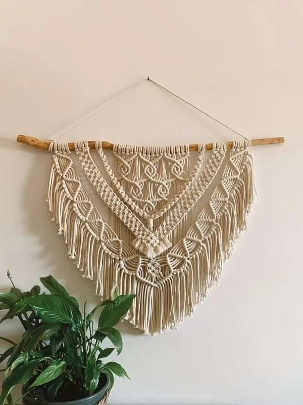 Painel de parede em macramé Reef em forma de leque, por cima de uma planta