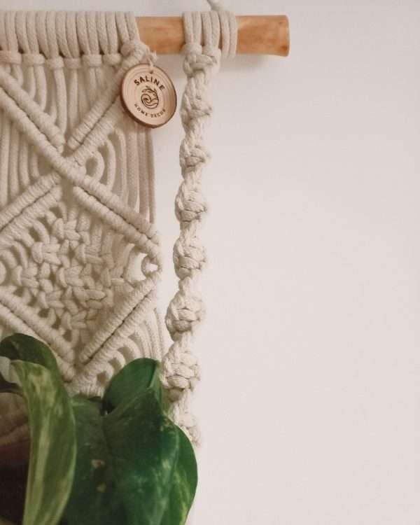 Pormenor dos losangos e do cordão em espiral do macramé Hera, com folhas de potos
